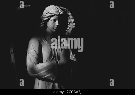 Angel statue praying in light and shadow. Black and white image. Stock Photo