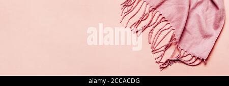 Minimal winter or autumn banner. Pink cozy scarf with tassels on pastel background Stock Photo