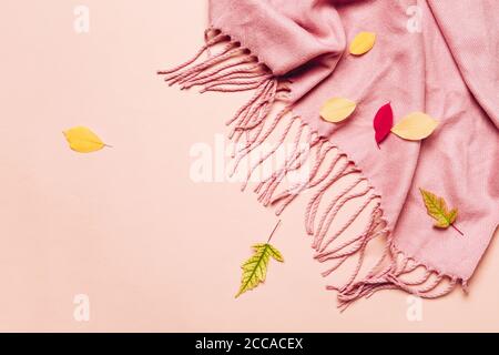 Pink cozy scarf with tassels and scattered leaves on pastel background. Hello autumn concept. Stock Photo