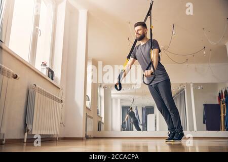 Professional sportsman doing a TRX chest press Stock Photo