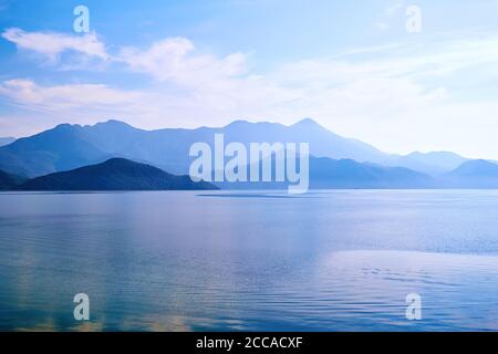 Twilight over the calm lake water and island with mountains. Famous Skadar lake in Montenegro. Nature background texture Stock Photo