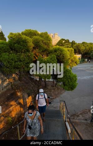 ATHENS, GREECE - 19 August 2020 - A couple of tourists wearing face masks to prevent the spread of the COVID-19 pandemic climb the stairs to Aeropagus Stock Photo