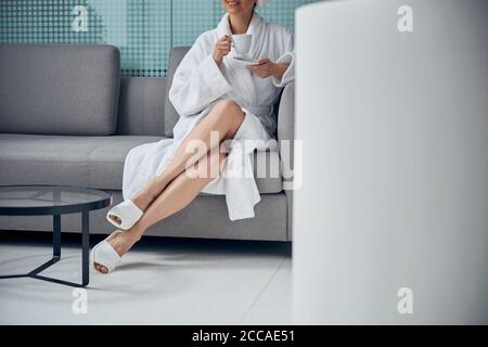 Pleased woman in a bathrobe relaxing on the sofa Stock Photo