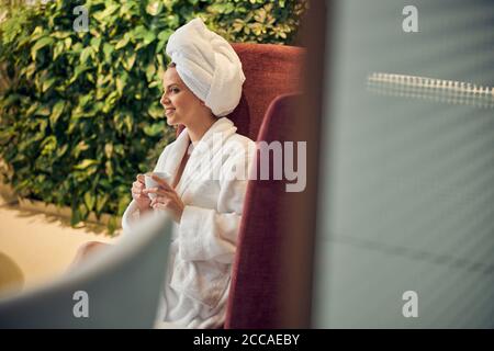 Pleased lady with a cup in her hands staring away Stock Photo