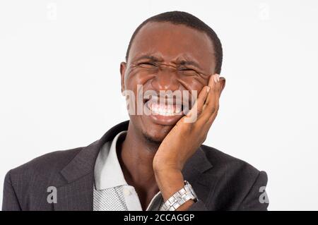 young man in suit standing on white background, hand on cheek, face disagreeable. Stock Photo