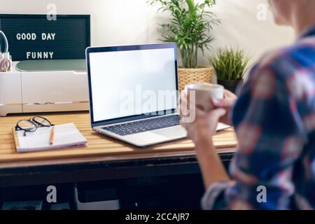 Cropped woman typing on laptop computer while sitting at home. Close up hands with mockup monitor. Distance learning online education and work Stock Photo