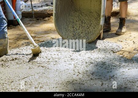 Construction process making of freshly poured cement wheelbarrow with shovel full of cement concrete of concrete mixer truck Stock Photo