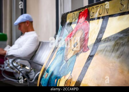 London, UK - April 17, 2019 - Paddington Bear Book Bench sculptures at Paddington station with a traveler in the background Stock Photo