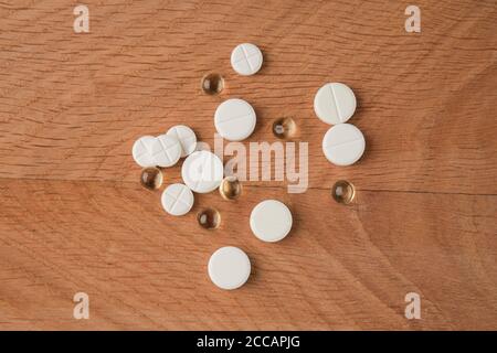 A bunch of various medicines, pills lying around without packaging, on a wooden board Stock Photo
