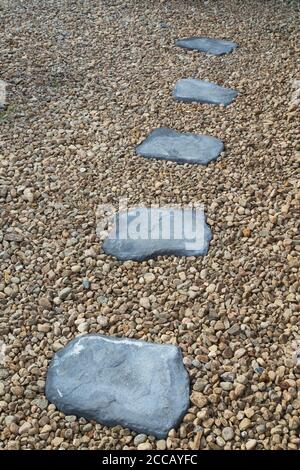 Grey path stones in bed of rocks in residential baclyard garden. Stock Photo