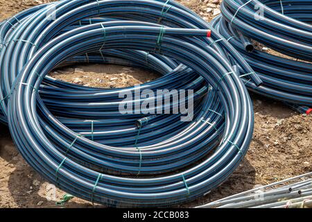 Black PVC hoses with a blue lines. Polyethylene tubing, pipe material at construction site. Stock Photo