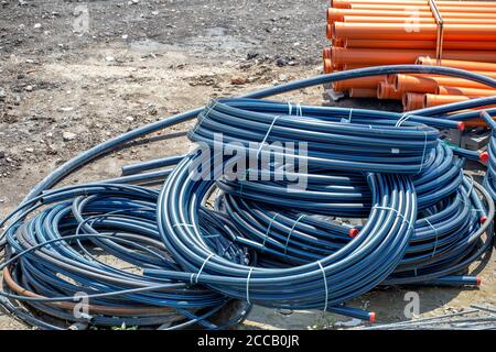 Coiled black PVC hoses with a blue lines. Polyethylene tubing, pipe material at construction site. Stock Photo