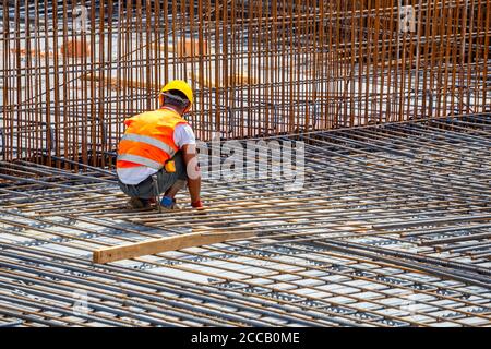 Construction worker surrounded by rebar, steel fixer tying steel reinforcement cage together. Stock Photo