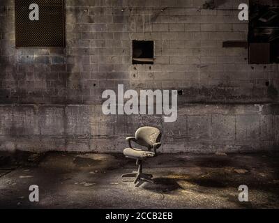 Old chair in abandoned industrial warehouse Stock Photo