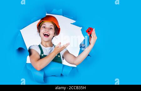 happy childhood. self-retracting metal tape measure. Little girl using a measuring tape. construction worker with tape measure. Cute kid as a construction worker. kid repairing home. copy space. Stock Photo