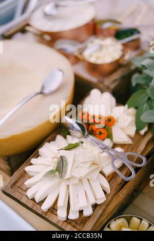 Melted cheese and a sprig of cherry tomatoes on a wooden plank with a melon on a blurred background. Stock Photo