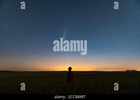 Silhouette of a man standing at night in a field outside the city. Starry night sky with comet Neowise C/2020 F3 Stock Photo