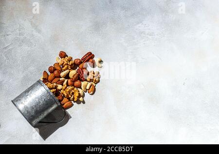 Various nuts on a light concrete background. Walnuts, almonds, hazelnuts and cashews, pecans. Organic vegetarian food, healthy snacks. Top view, copy Stock Photo