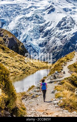 Hiking girl in New Zealand Mt Cook nature mountain. Alone hiker walking on popular trail Mueller Hut route in Mount Cook National Park mountains Stock Photo