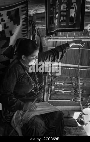 A Navajo woman weaves a rug in a hogan at Monument Valley, Utah, USA Stock Photo