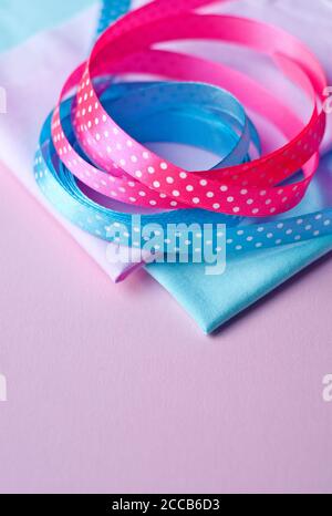 Cotton fabric of different colors and satin ribbons with polka dots on a pink background. Space for text, top view Stock Photo