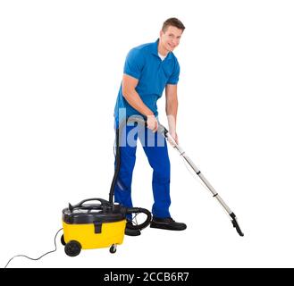 Young Man Cleaning Floor Using Vacuum Cleaner On White Background Stock Photo