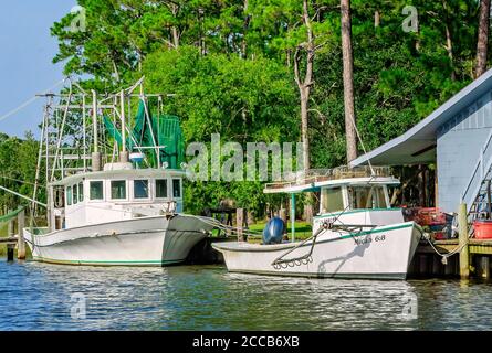 An oyster boat and shrimp boat are docked in front of a home on Fowl River, July 6, 2019, in Coden, Alabama. Stock Photo