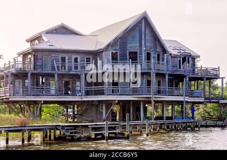 An abandoned house sits on stilts along Fowl River, July 6, 2019, in Coden, Alabama. Most of the windows have been broken. Stock Photo