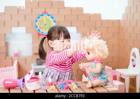 toddler girl pretend play babysitting with baby doll at hom Stock Photo