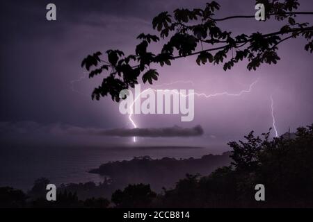 A flash of lightning strikes behind a cloud over the Pacific Ocean, seen from the Osa Peninsula in Costa Rica. Stock Photo