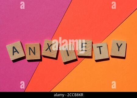 Anxiety in wooden alphabet letters on isolated pink, red and orange coloured backround Stock Photo