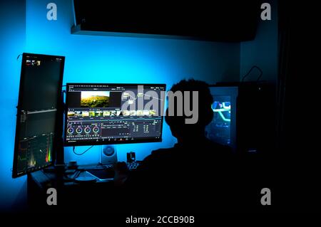 Male working on video editing software at home on desktop computer with 2 monitors. Stock Photo