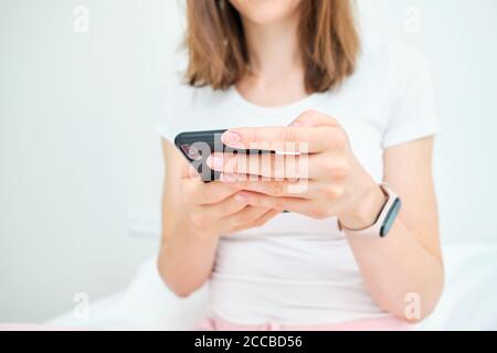 Woman uses smartphone at home on bed. Stock Photo
