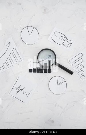business analysis and statistics concept, desk with mixed graphs and charts with magnifying glass on it Stock Photo