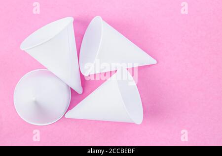 Disposable paper cone water cups on pink background. Stock Photo