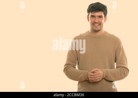Studio shot of young happy Persian man smiling Stock Photo