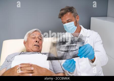 Dentist Examining Dental Xray Of Old Senior Stock Photo