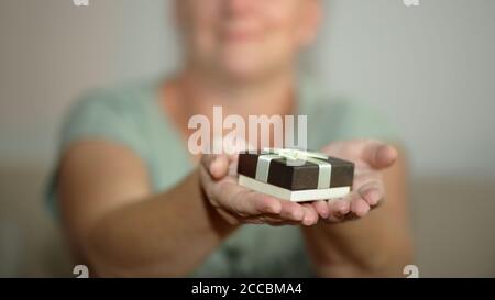Woman holds in her hands small decorative gift present box tied with bow Stock Photo