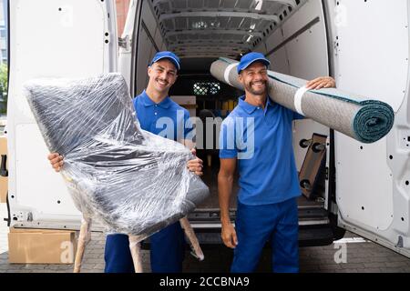 Movers Doing Furniture And Carpet Removal From Truck Or Van Stock Photo