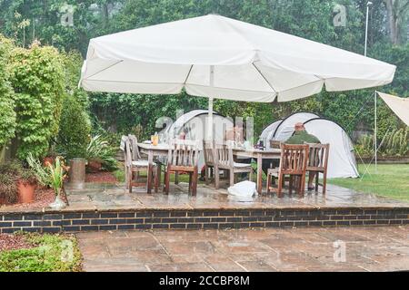 Staycation camping in a back garden on a rainy summer day during the coronavirus epidemic, August 2020. Stock Photo