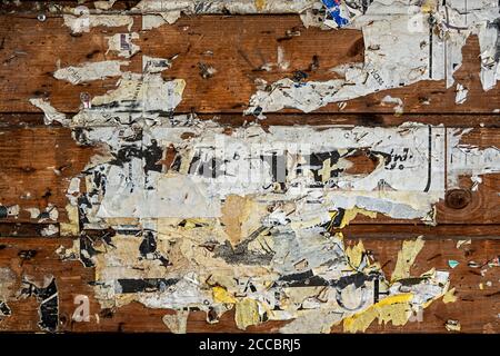 brown wooden wall with teared placards Stock Photo