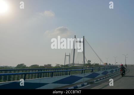 Kolkata, West Bengal, India - 25th July 2020 : Sun rays in blue sky over 2nd Hoogly Bridge, The bridge connects Howrah and Kolkata. Stock Photo