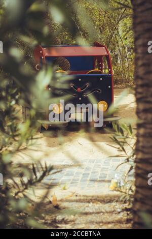 Vertical shot of a car-shaped playground with palm tree leaves on the foreground Stock Photo