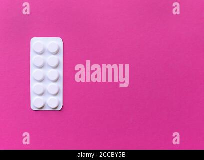 White blister of pills on pink background. Simple flat lay with pastel texture with copy space. Medical concept. Stock photography. Stock Photo