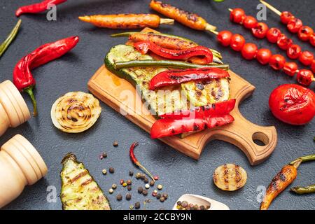 grilled vegetables on a wooden board on a black table Stock Photo