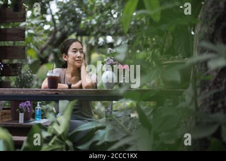 https://l450v.alamy.com/450v/2ccc1kx/woman-resting-outdoors-sitting-on-wooden-chair-with-iced-coffee-in-nature-garden-2ccc1kx.jpg