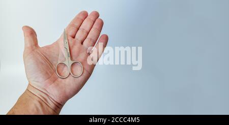 Man's open hand with a small manicure scissors in his palm, isolated on white background. copy space Stock Photo