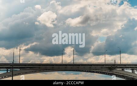 Empty bridge against sky - side view. Sun beams shining through dramatic white clouds. Urban, infrastructure development, transportation concept Stock Photo