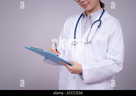 Healthy concept : Young Asian doctor writing on clipboard  for patient chart , anonymous face. Beautiful Asia female model in her 30s Stock Photo