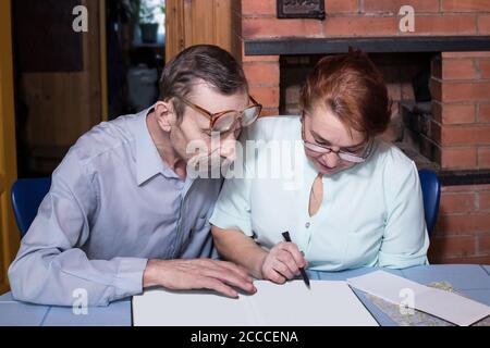 Senior couple in the country house discuss something, album with blank pages, copy space Stock Photo